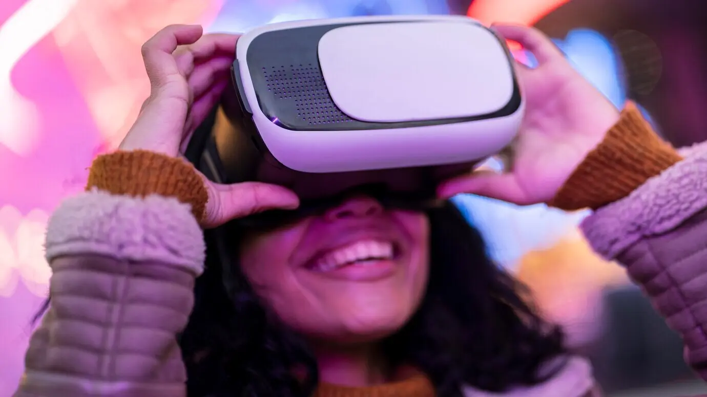 Улыбающаяся женщина, пользующаяся очками виртуальной реальности.